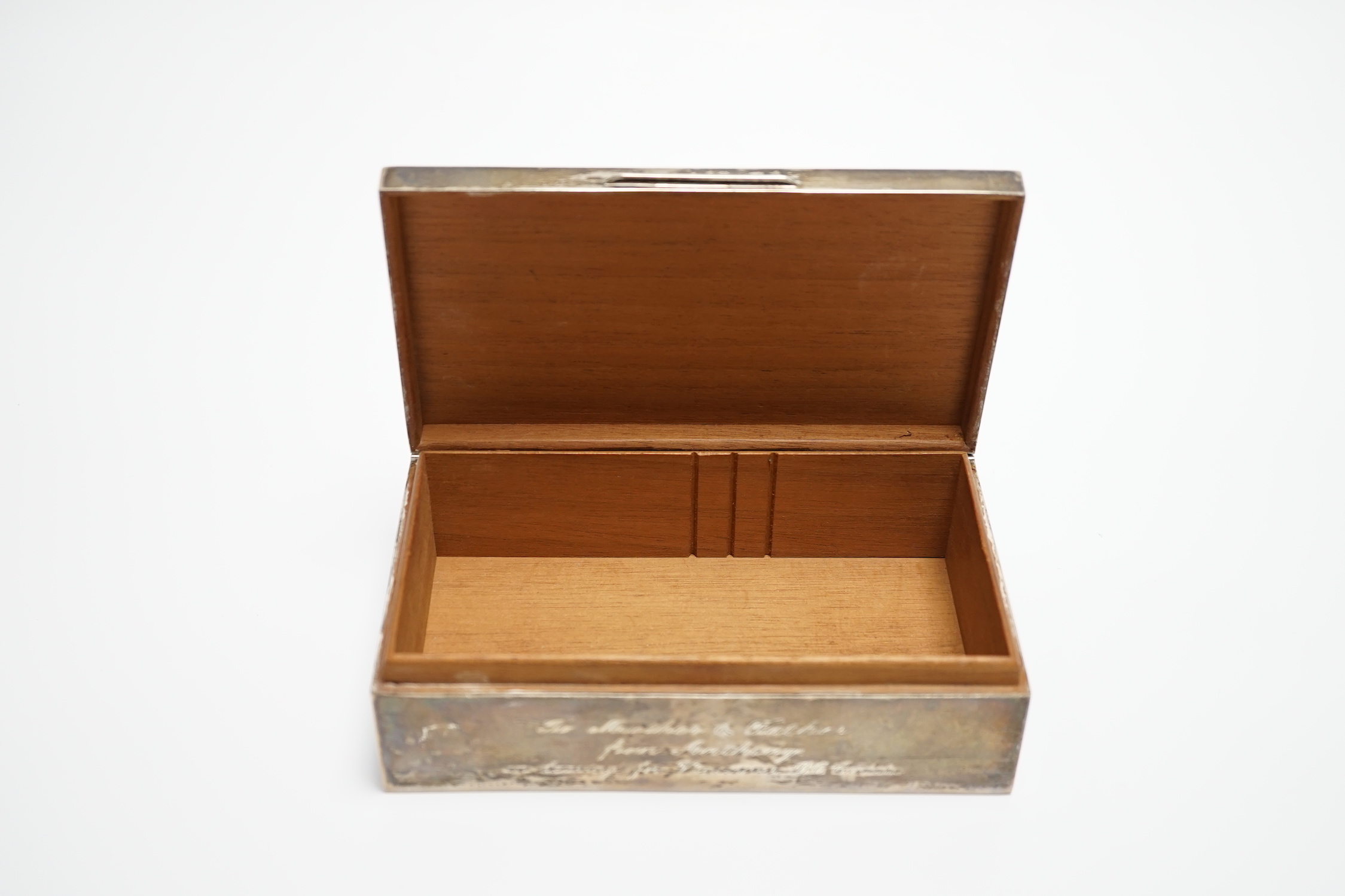 A modern part engine turned silver cigarette box, with engraved inscription, 16cm and a silver serviette ring.